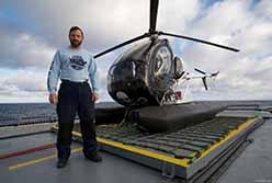 Volunteer Chris Aultman with helicopter in ODA shirt