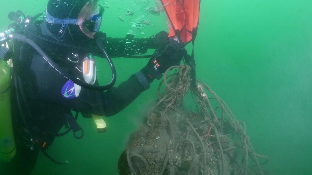 Scuba diver attaches float bag to abandoned fishing gear