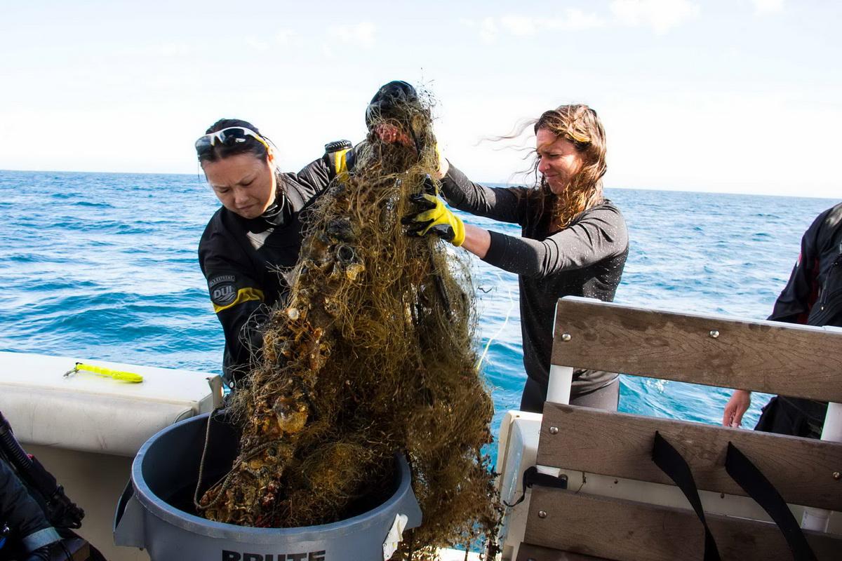 Female crew removes abandoned fishing net from ocean