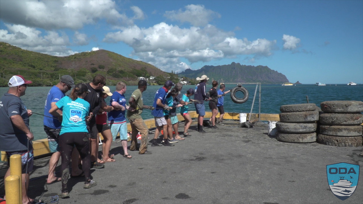 Crew lines up to play tug of war with tire